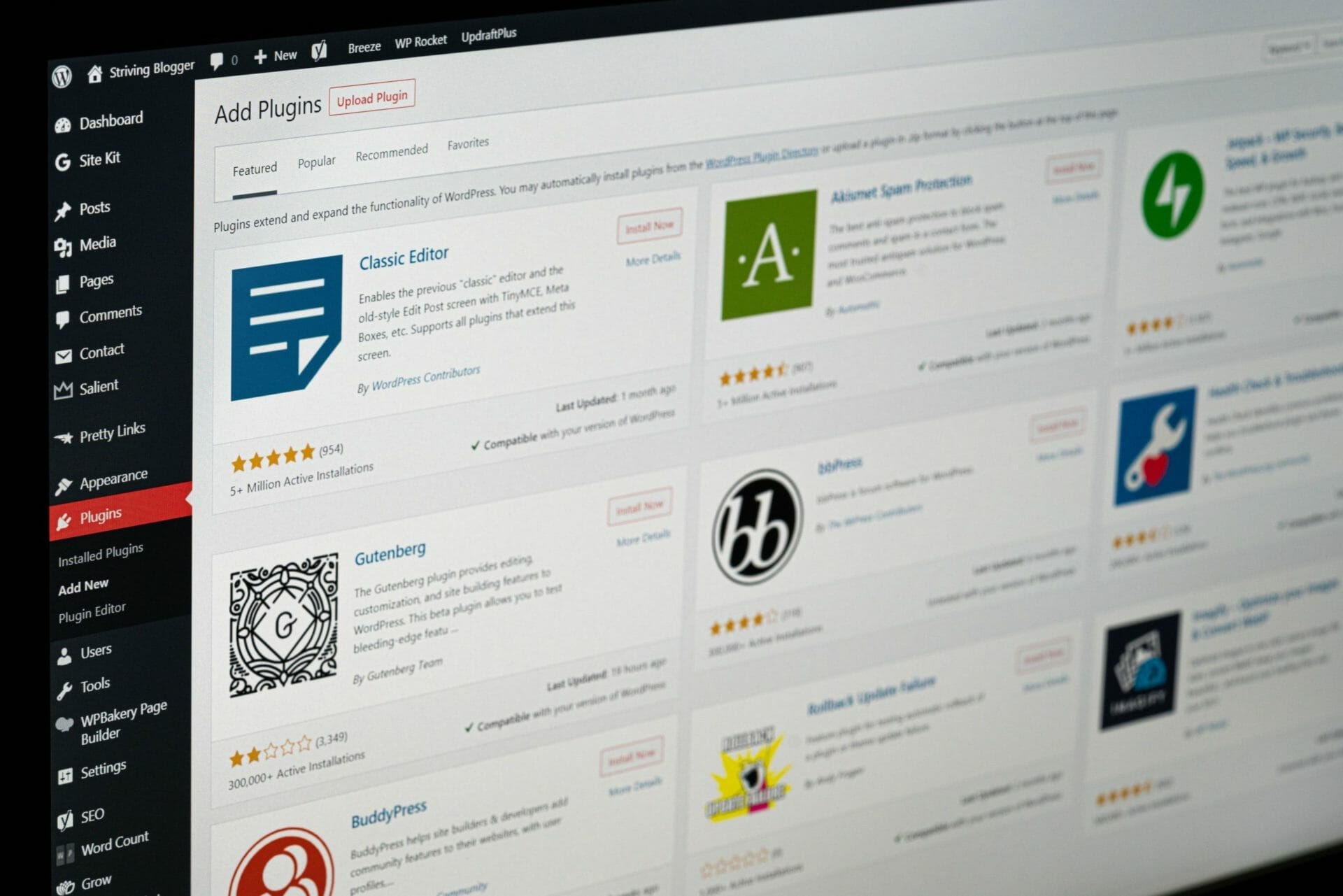 A computer screen displaying the WordPress admin panel with the "Add Plugins" page open, showcasing different plugin options including Classic Editor, Gutenberg, and others.