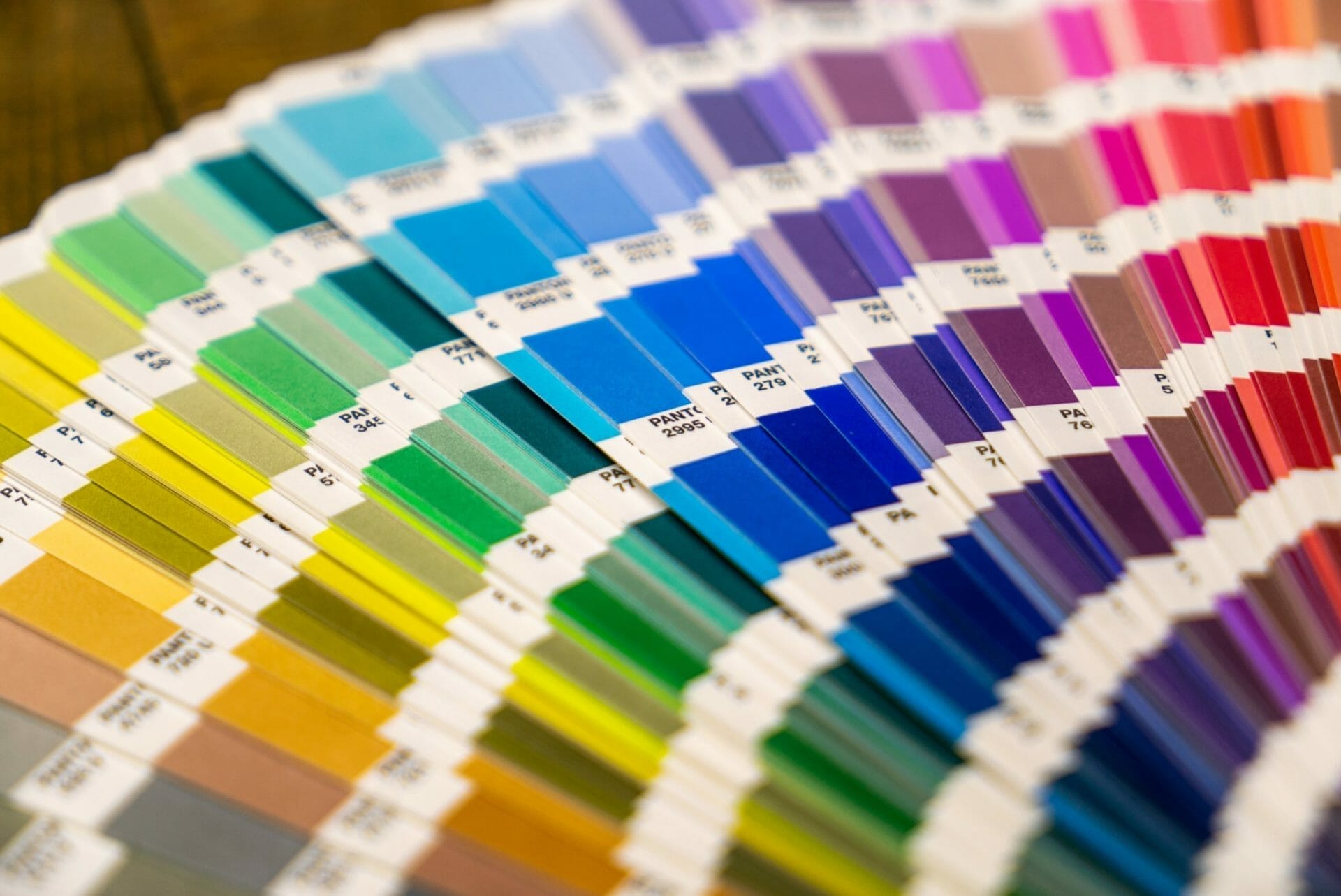A color swatch book displaying a fan of paint color samples ranging from yellows and greens to blues, purples, and pinks, each labeled with a unique identifier.